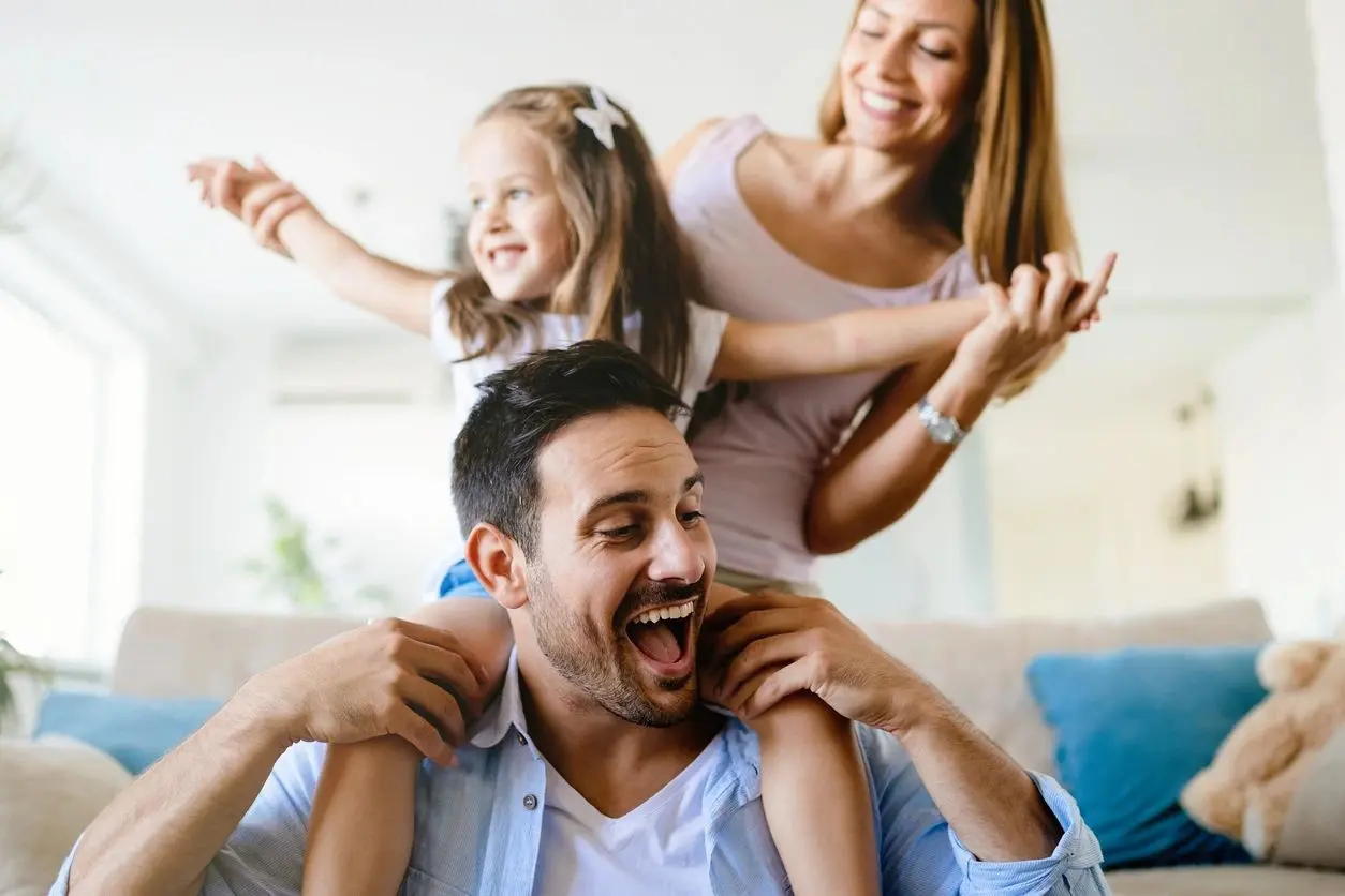 A man and woman are playing with their daughter.