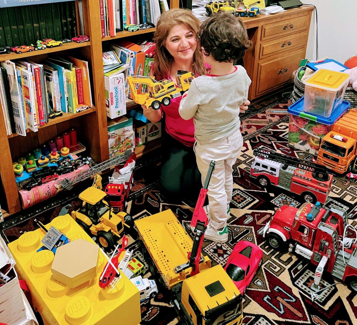 A woman and child playing with toys in the floor.